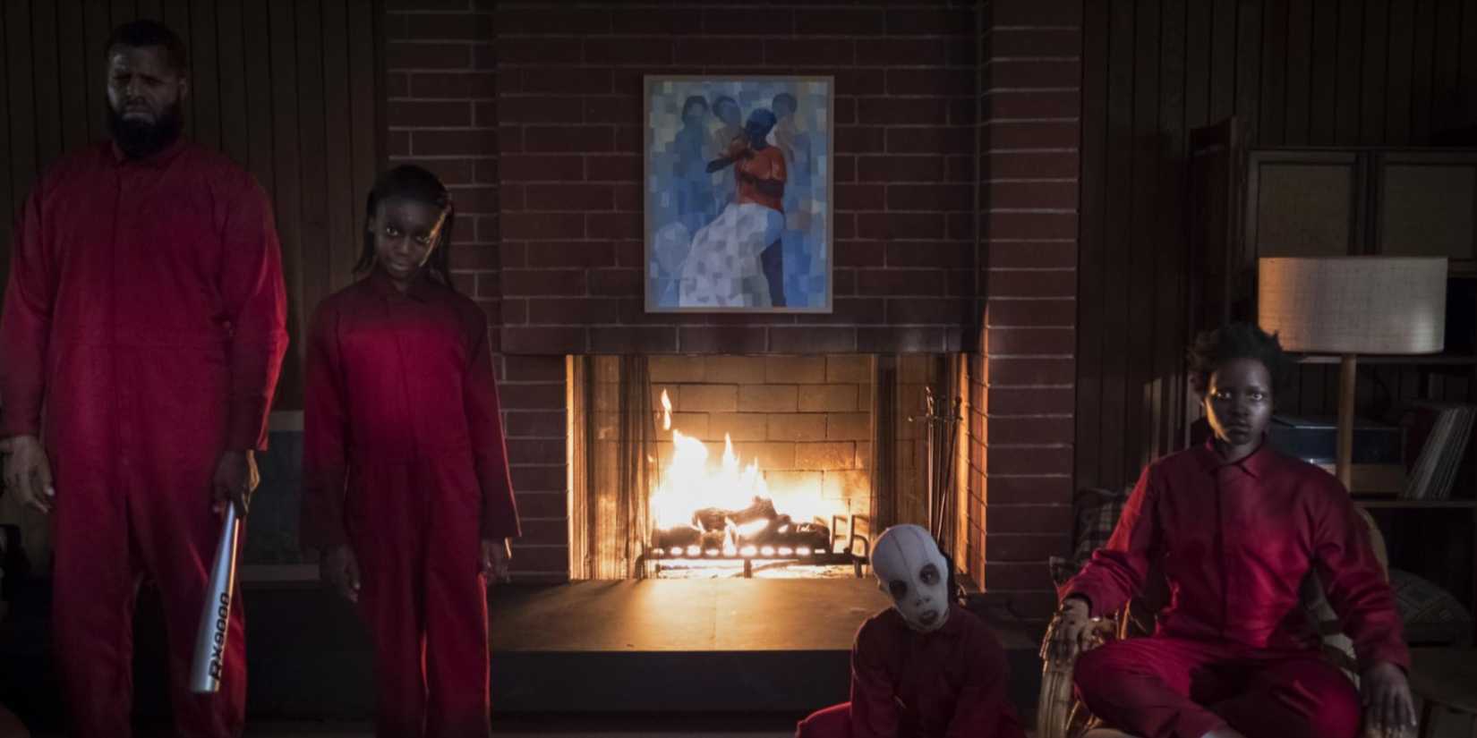 The creepy doubles of the main characters in red jumpsuits standing in front of them by the fireplace.